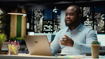 afrikansk amerikan kille vinka på webb konferens med aktieägare, delta en avlägsen chatt på internet från kontor skrivbord. anställd nätverk, förhandlings med verkställande styrelse. kamera b. video