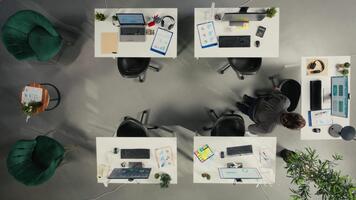 topo baixa Visão do colegas de trabalho dentro multinacional companhia cumprimento cada de outros dentro escritório, resolução diariamente tarefas com documentos e diagramas. profissional diverso trabalhos equipe discute corporativo metas. Câmera uma. video