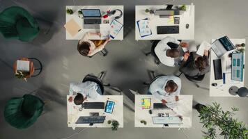 Top down view of diverse coworkers analyzing business data and metrics during report sharing session in boardroom. Professional work team discuss forecasting and management insights. Camera A. video