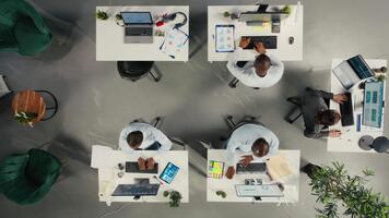 topo baixa Visão ampliação dentro do empregados revendo documentação e desempenho relatórios. colegas dentro uma profissional escritório configuração colaborar em planejamento, projeções e mercado pesquisar. Câmera uma. video