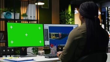 verde schermo Il prossimo per africano americano donna Lavorando su gioco sviluppando, utilizzando multiplo monitor a il ufficio. femmina ingegnere la creazione di un' futuristico navicella spaziale stazione su Software. telecamera b. video