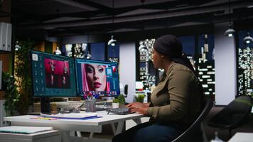 afrikansk amerikan fotograf använder sig av Foto redigering för digital design, dubbel monitorer visa Avancerad redigering programvara för designer arbetssätt på bild retuschering, kontrast justeringar. kamera a. video