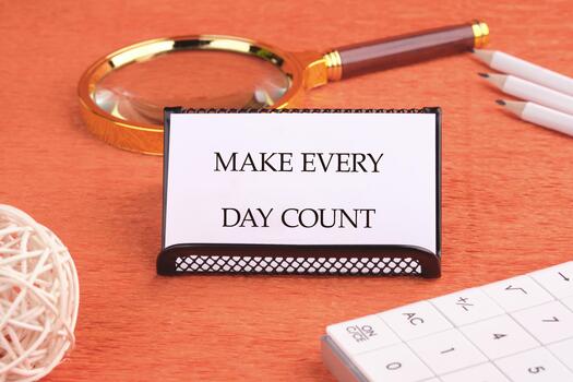 Concept words MAKE EVERY DAY COUNT written on a business card on a black stand in front of an orange background photo