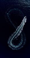 fuco superiore Visualizza di un' motoscafo la creazione di un infinito ciclo continuo su turchese mare, che rappresentano libertà, futuro, infinito avventura, e il spirito di estate nel natura. verticale formato. video