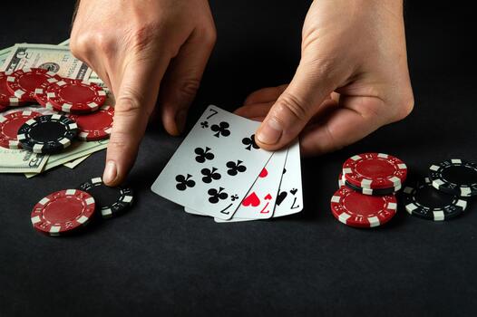 The player bets on a winning combination of three of a kind or a set in a poker game on a black table with chips and money in a club. photo