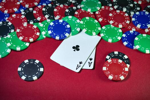 Players are engaged in a lively poker game featuring a mix of colored chips scattered across a red table along with two aces facing up, creating a thrilling atmosphere photo
