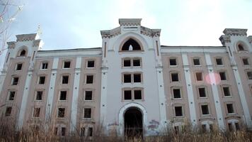 Tall derelict structure, high arched window dominates facade, ghost resembling suicide victim stands ready to fall, autumn sky and empty shell amplify atmosphere of sorrow and legend. video