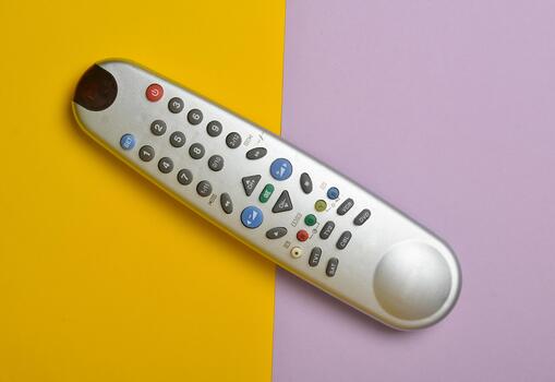 Multi-function push-button TV remote control on a colored pastel background. Top view. photo