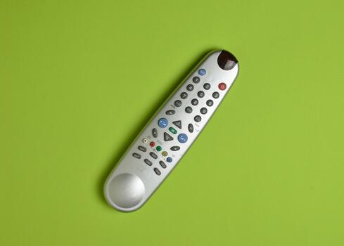 Multi-function push-button TV remote control on a green paper background. Top view. photo