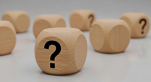Wooden dice displaying question marks on a reflective surface symbolizing uncertainty and the search for answers in business education and personal life creating a mood of curiosity and inquiry photo