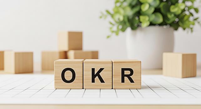 Wooden blocks displaying OKR acronym on a bright desk with a plant symbolizing objectives and key results for business strategy and goal setting in a modern minimalist office environment photo