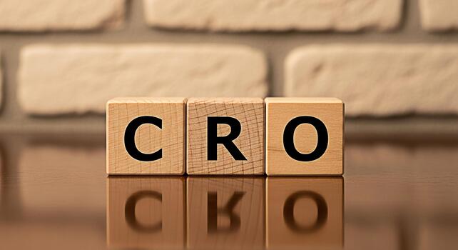 Wooden blocks displaying CRO on a reflective surface against a brick wall symbolizing Conversion Rate Optimization and its importance in digital marketing and business growth strategies photo