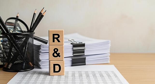 Research and development concept with wooden blocks displaying RD on a desk with documents pencils and a calculator representing innovation analysis and strategic planning in a professional setting photo