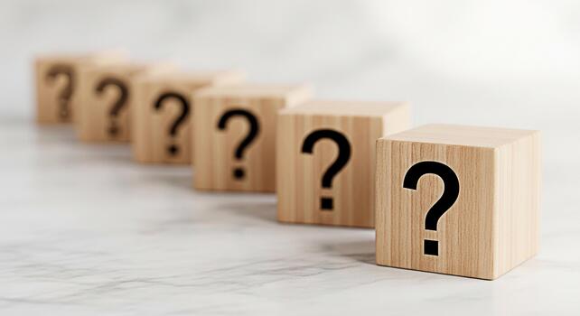 A row of wooden blocks displaying question marks on a marble surface representing uncertainty and the need for answers creating a sense of mystery and intellectual curiosity in a bright clean setting photo