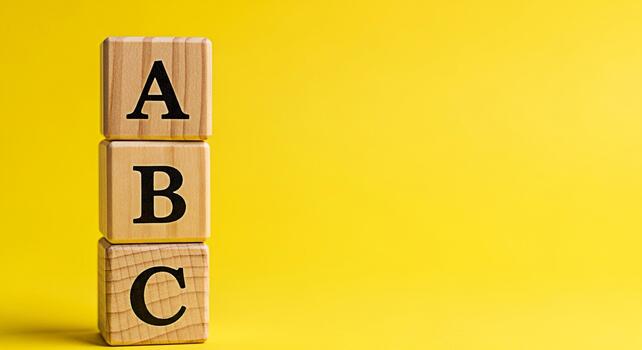 Wooden alphabet blocks stacked vertically on a bright yellow background representing early childhood education and learning the ABCs in a fun and engaging way promoting literacy and cognitive developm photo