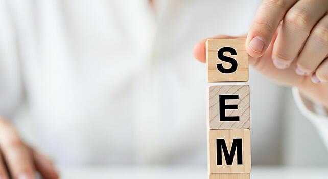 Hand arranging wooden blocks spelling SEM on a white surface symbolizing Search Engine Marketing and optimization strategies for business growth and online success in a bright minimalist setting photo