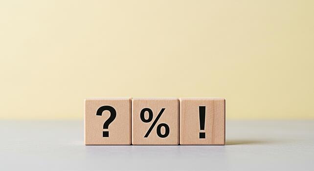 Wooden blocks displaying question mark percentage sign and exclamation point on a neutral surface symbolizing uncertainty finance and emphasis in a simple educational setting photo