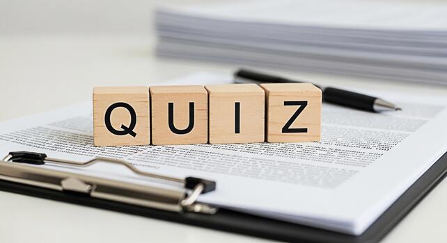 Wooden blocks spelling QUIZ resting on a clipboard with documents in a bright office setting suggesting learning testing knowledge and assessment in an educational or business context photo