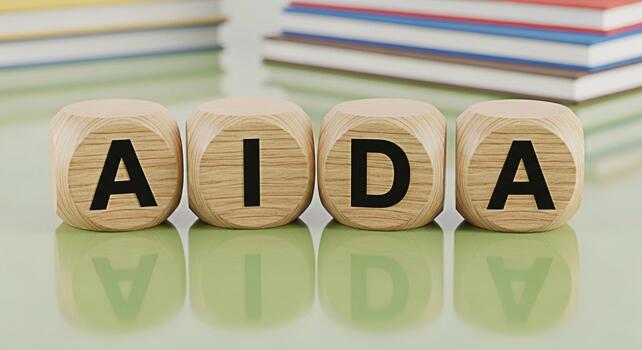 Wooden cubes displaying AIDA model on a green table with books in the background representing marketing strategy and customer journey creating awareness interest desire and action for business success photo