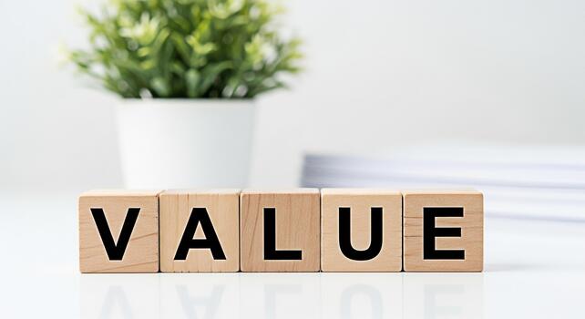 Wooden blocks spelling VALUE on a clean white desk with a potted plant representing core values and business ethics in a minimalist bright and professional workspace environment photo
