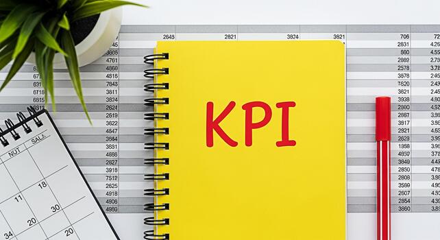 Yellow notepad displaying KPI on a desk with financial data calendar pen and plant symbolizing key performance indicators and business performance analysis in a modern office setting photo