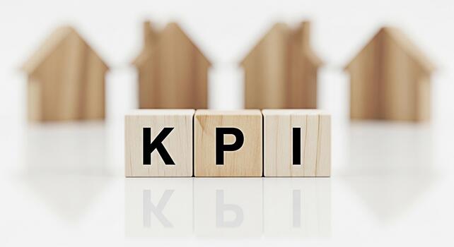 Wooden blocks displaying KPI with blurred house shapes in the background representing key performance indicators for real estate success and investment growth in a bright minimalist setting photo