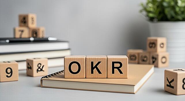 Wooden blocks displaying OKR on a notebook in a bright office setting symbolizing Objectives and Key Results for business goal setting and achievement promoting productivity and strategic planning photo