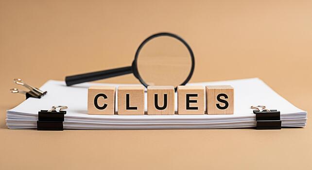 Magnifying glass hovering over wooden blocks spelling CLUES on a stack of papers suggesting investigation and problemsolving in a neutral studio setting creating a sense of mystery and intrigue photo