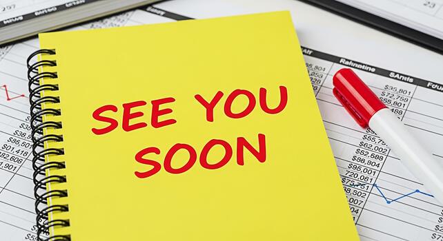 Bright yellow notebook displaying See You Soon message on a financial report background conveying a sense of anticipation and farewell in a business or personal context with a red marker nearby photo