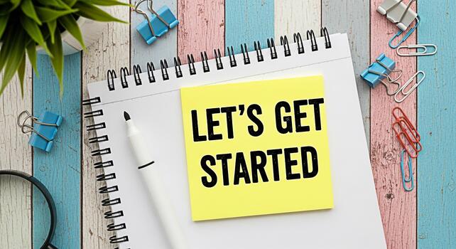 Overhead shot of a notepad with a yellow sticky note that reads Lets Get Started on a colorful wooden desk symbolizing motivation and new beginnings in a vibrant workspace photo