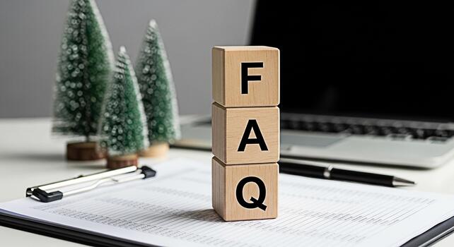 Wooden blocks displaying FAQ on a modern white desk with Christmas trees and a laptop computer representing frequently asked questions and support during the holiday season in a professional setting photo