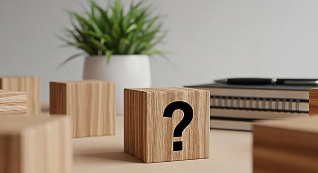 Wooden block displaying a question mark on a desk with a plant and notebook symbolizing uncertainty and the need for answers in a modern minimalist workspace environment photo