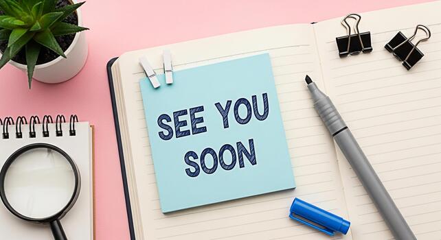 Office desk setup with a notepad displaying See You Soon message surrounded by stationery creating a farewell or anticipation mood in a bright and organized workspace photo