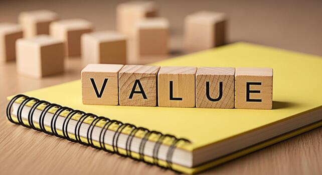 Wooden blocks spelling VALUE resting on a yellow notebook on a wooden surface representing core values business ethics and the importance of integrity in a professional and academic setting photo