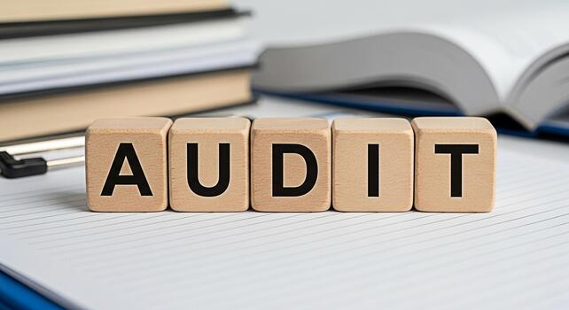 Wooden blocks spelling AUDIT on lined paper with books in the background representing financial examination and verification in a professional and meticulous environment conveying accuracy and complia photo