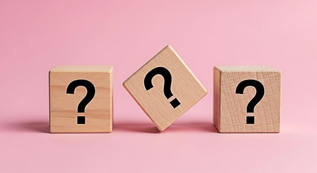 Three wooden cubes displaying question marks on a pink background representing uncertainty and the need for answers in a simple minimalist studio setting evoking curiosity and problemsolving photo