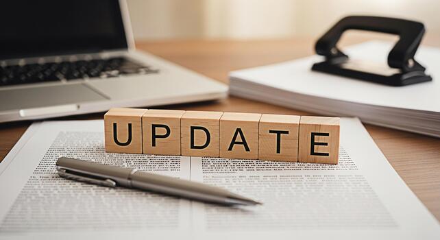 Wooden blocks spelling UPDATE rest on a document in a modern office setting symbolizing the need for continuous improvement and adaptation in business and personal growth with a laptop and office supp photo