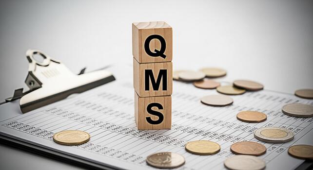 Wooden blocks spelling QMS placed on a financial report with scattered coins representing quality management systems in a business environment conveying a sense of precision and financial control photo