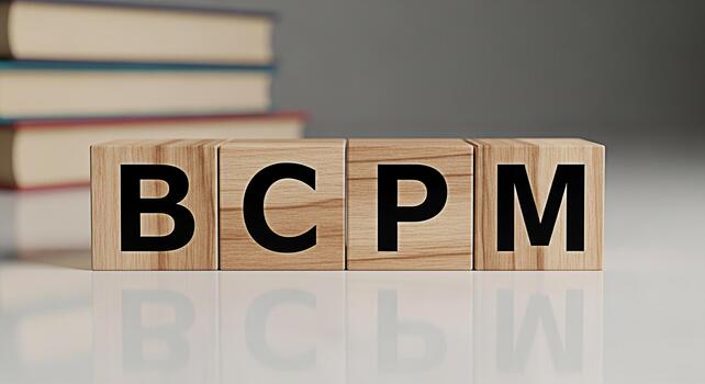 Wooden blocks spelling BCPM on a white surface with books in the background representing business continuity planning and management in a professional and educational setting conveying a sense of orga photo
