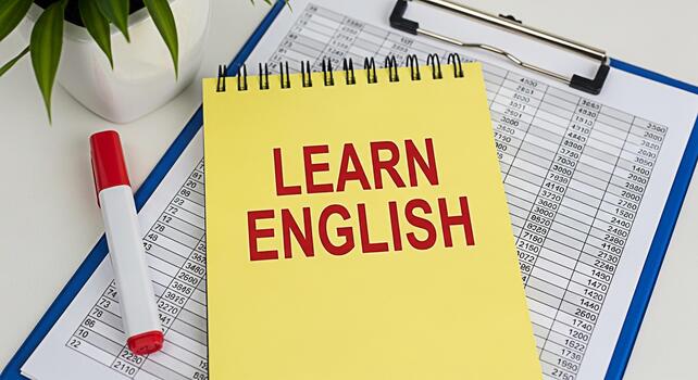 brillante amarillo cuaderno con aprender Inglés texto en un blanco escritorio con un portapapeles y un rojo marcador creando un educativo y motivacional atmósfera para idioma aprendizaje y habilidad desarrollo foto