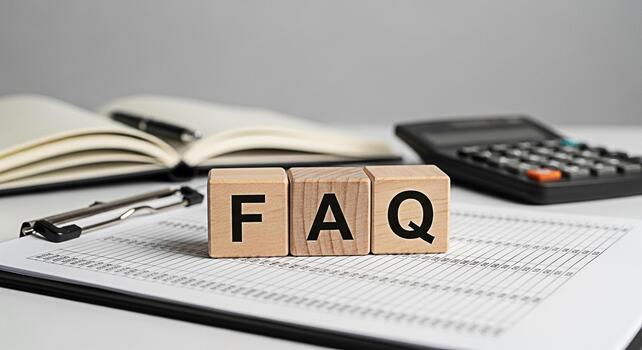 Wooden blocks spelling FAQ on a clipboard in a bright office setting representing frequently asked questions and providing helpful information with a calculator and notebook in the background photo