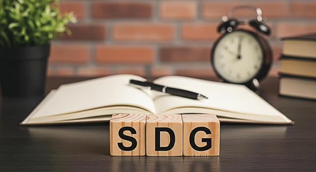 Wooden blocks spelling SDG on a desk with an open notebook pen books clock and plant representing sustainable development goals and a commitment to global responsibility in a modern workspace photo