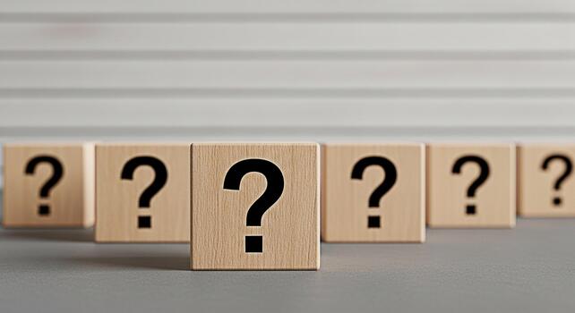 Wooden blocks displaying question marks in a row on a gray surface symbolizing uncertainty and the search for answers in a minimalist and clean studio setting creating a sense of curiosity and inquiry photo