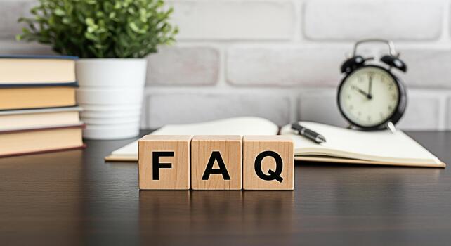 Wooden blocks spelling FAQ on a desk with books a plant a notebook a pen and an alarm clock against a white brick wall representing frequently asked questions and knowledge resources photo