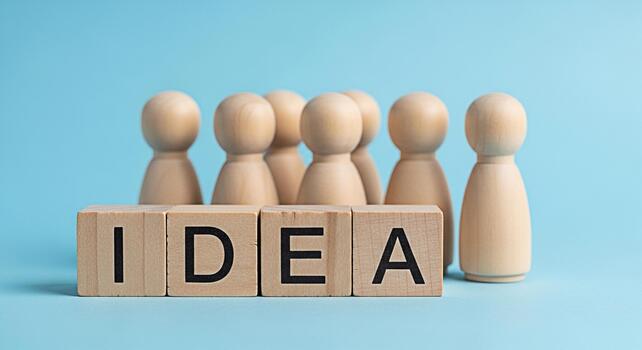 Wooden figures standing behind the word IDEA on wooden blocks against a light blue background representing teamwork brainstorming and the generation of innovative solutions conveying a sense of collab photo