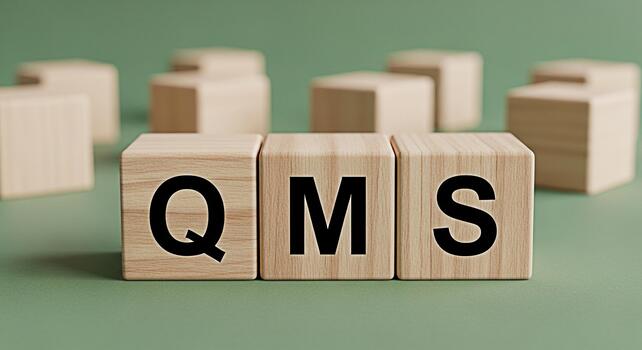 Wooden blocks displaying QMS on a green surface representing quality management system implementation and adherence to standards in a business environment conveying a sense of order and compliance photo