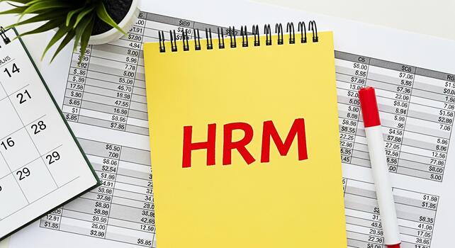 HRM Concept on Yellow Notepad with Calendar and Financial Data Sheets Displaying Human Resources Management in a Business Environment Illustrating Planning and Organization photo