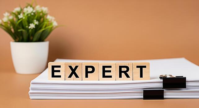 Wooden blocks spelling Expert on a stack of papers in a bright office setting symbolizing knowledge competence and professional skill creating a mood of trust and reliability in business and consultin photo