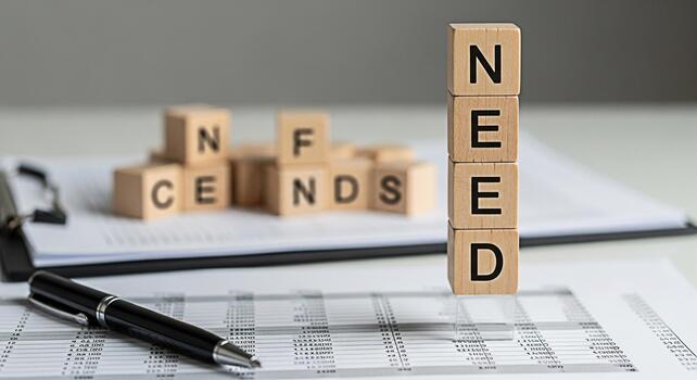 Wooden blocks spelling NEED stand prominently on financial documents with a sleek pen symbolizing financial requirements and planning in a professional office setting creating a mood of fiscal respons photo