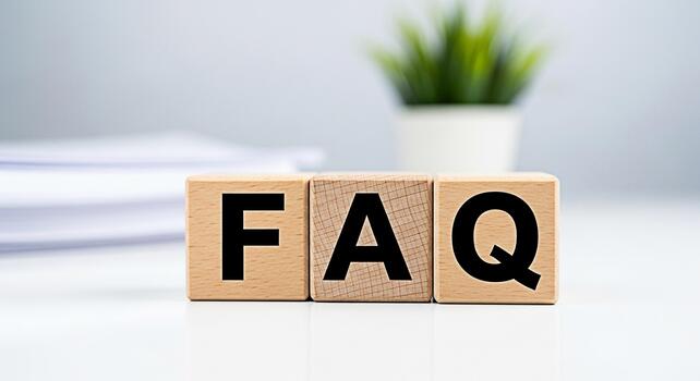 Wooden blocks displaying FAQ on a clean white desk with a blurred plant in the background representing frequently asked questions and information accessibility in a modern and minimalist setting photo